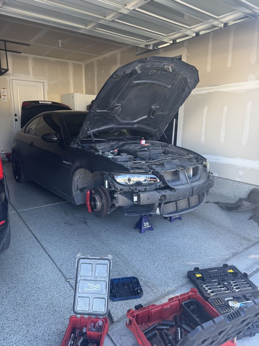 BMW in a garage on jack stands with the front bumper off
