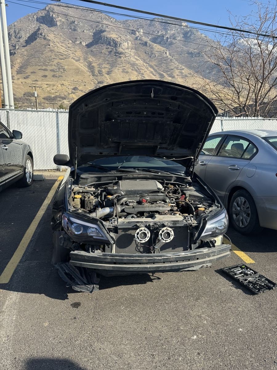Subaru with the front bumper off in a parking lot
