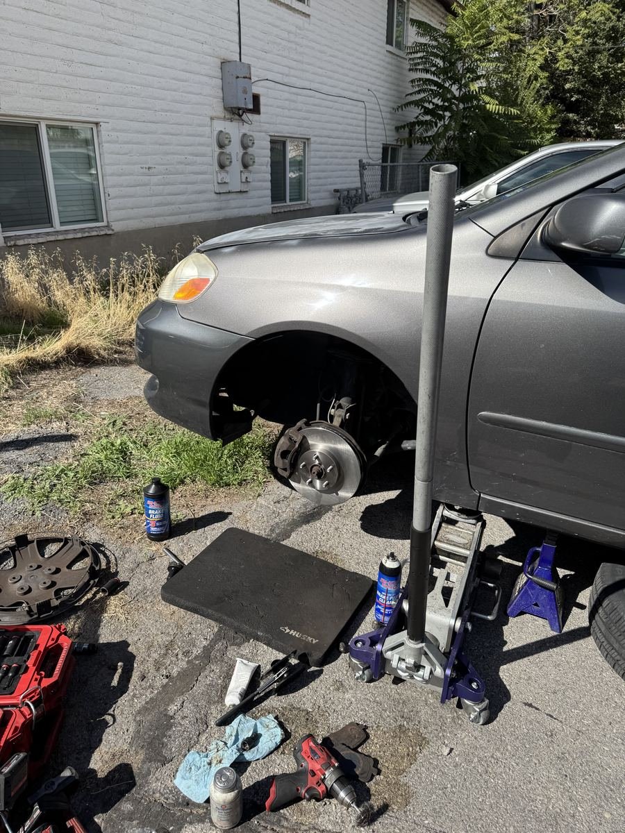 Gray Toyota on a jack with a front wheel off and a new rotor
