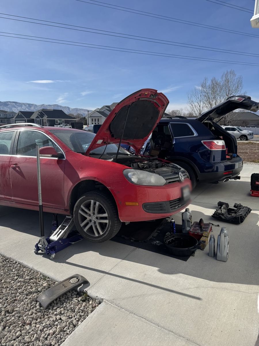 Red Volkswagen Golf on a jack with the hood up